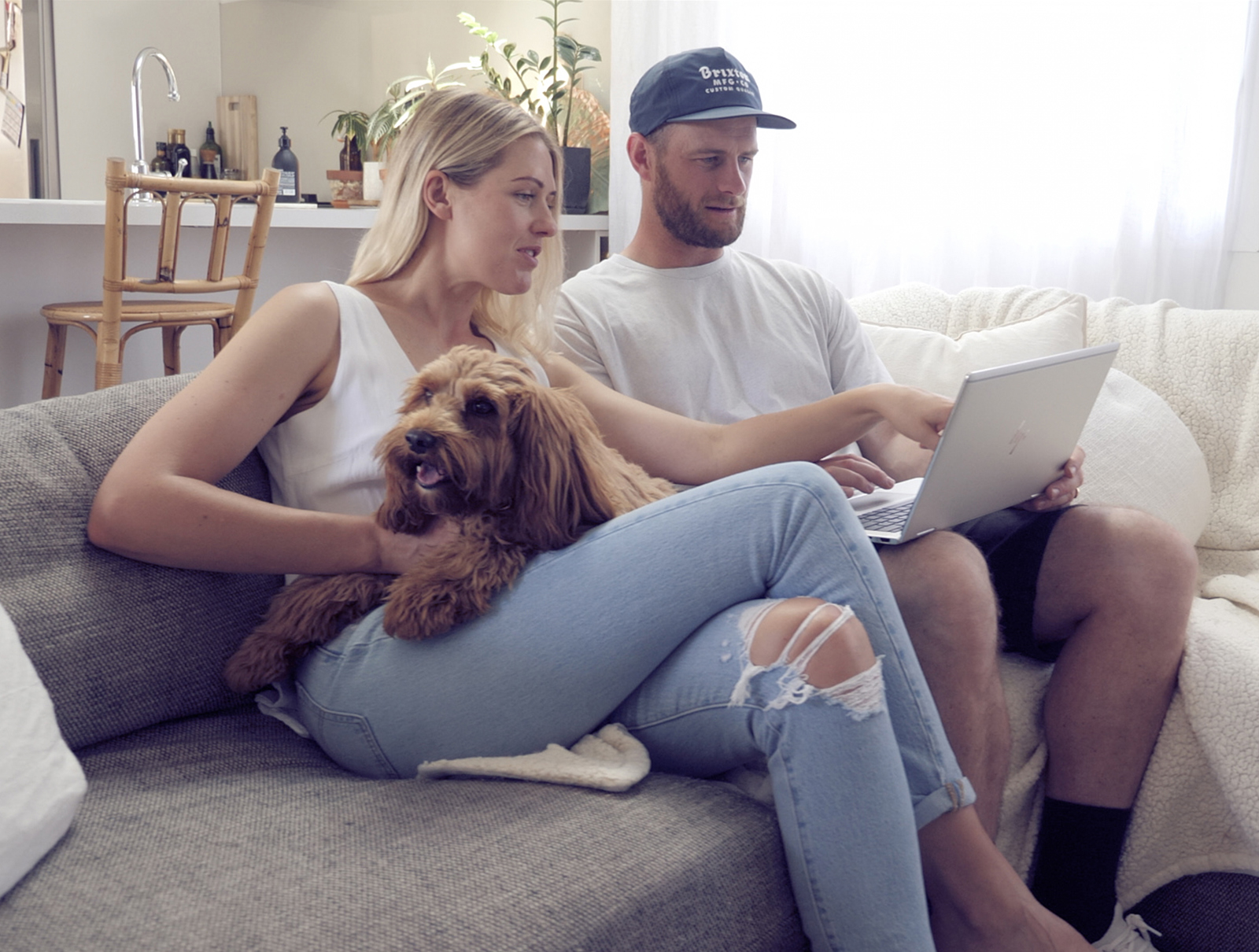 Couple sitting on a couch looking at a laptop