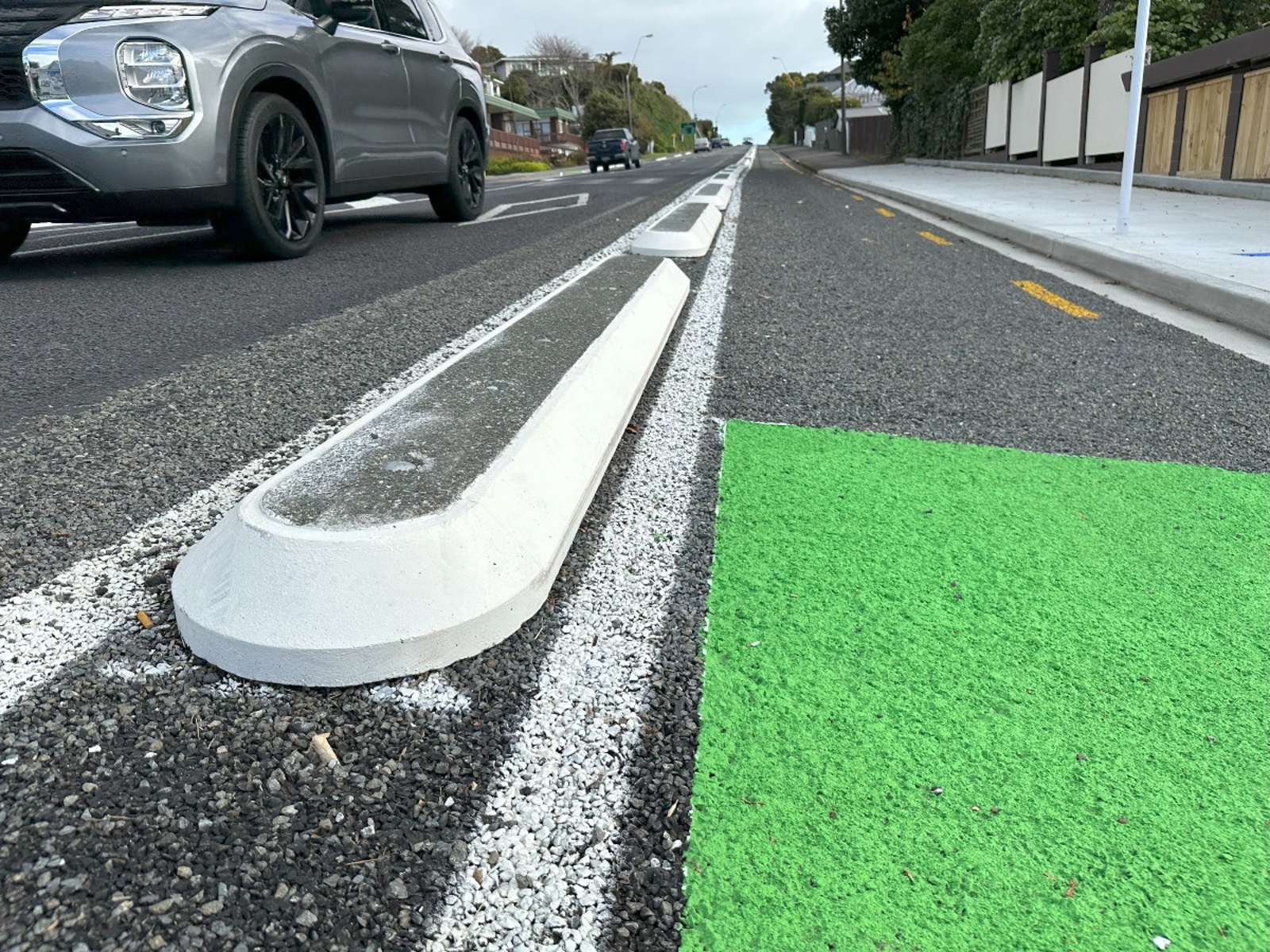Concrete cycle separator on the road with a green painted cycle lane